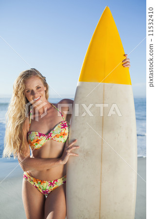 Gorgeous blonde surfer in bikini holding her board 11532410