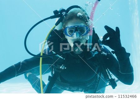 Woman on scuba training submerged in swimming pool making ok sig 11532466