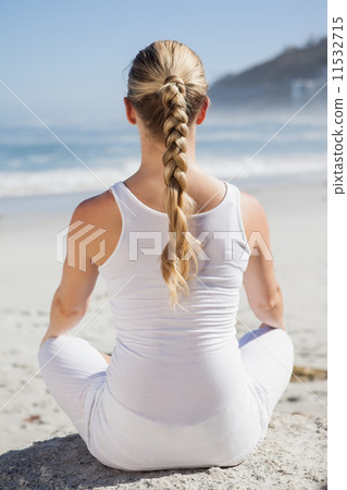 Blonde woman sitting in lotus pose on beach Blonde woman sitting in lotus pose on beach 11532715
