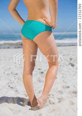 Lower half of fit woman standing on beach 11532769