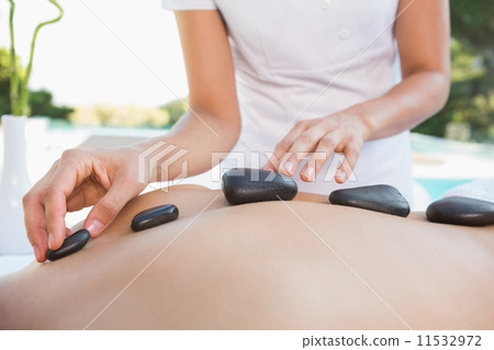 Man getting a hot stone massage poolside 11532972