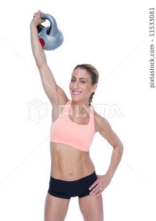 Female blonde crossfitter lifting kettlebell above head smiling Female blonde crossfitter lifting kettlebell above head smiling 11533081