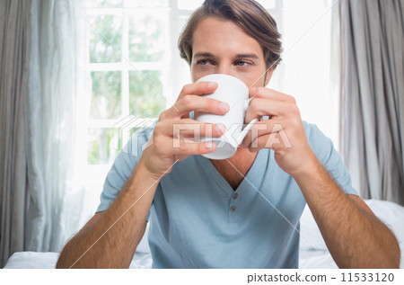 Handsome man sitting on bed drinking coffee 11533120
