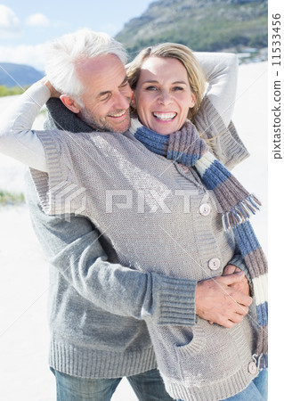 Carefree couple hugging on the beach in warm clothing 11533456