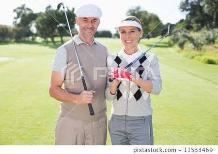 Golfing couple smiling at camera holding clubs Golfing couple smiling at camera holding clubs 11533469