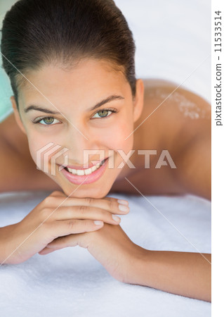 Smiling brunette lying on towel looking at camera 11533514