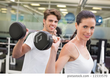 Fit couple lifting barbells together 11533570