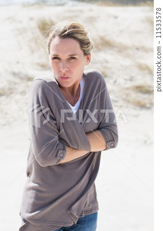 Shivering blonde woman standing on the beach 11533578