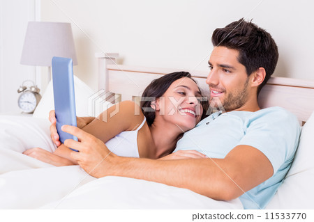 Attractive couple lying in bed with tablet pc Attractive couple lying in bed with tablet pc 11533770