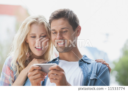Cute young couple looking at smartphone Cute young couple looking at smartphone 11533774