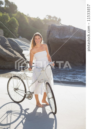Beautiful blonde in white sundress standing with bike on the bea Beautiful blonde in white sundress standing with bike on the bea 11533857