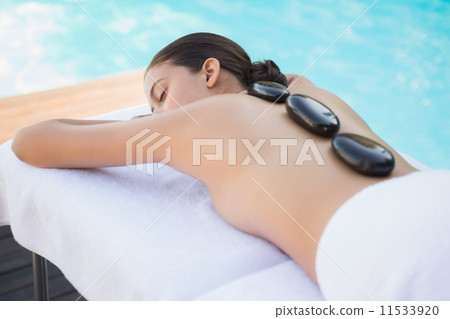 Relaxed brunette lying poolside having a hot stone massage 11533920