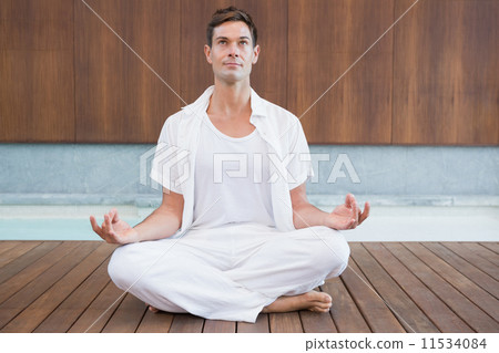 Handsome man in white meditating in lotus pose Handsome man in white meditating in lotus pose 11534084