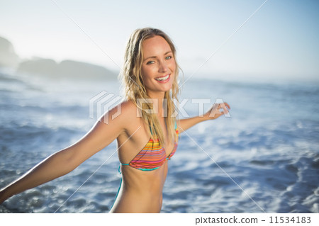 Content blonde standing on the beach in bikini with arms out Content blonde standing on the beach in bikini with arms out 11534183