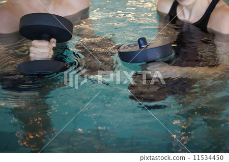 Man and woman holding foam dumbbells in the pool Man and woman holding foam dumbbells in the pool 11534450