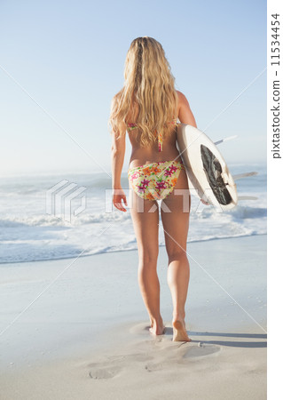 Gorgeous blonde surfer in bikini holding her board Gorgeous blonde surfer in bikini holding her board 11534454