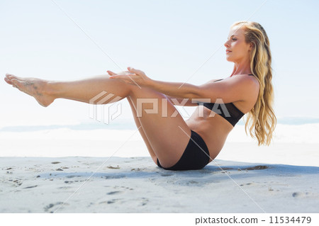 Fit blonde in core balance pilates pose on the beach Fit blonde in core balance pilates pose on the beach 11534479