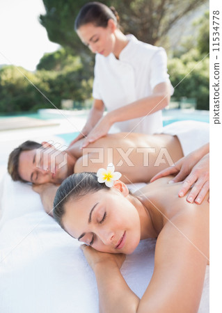 Attractive couple enjoying couples massage poolside 11534778