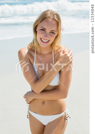 Beautiful blonde in white bikini smiling at camera on the beach 11534848