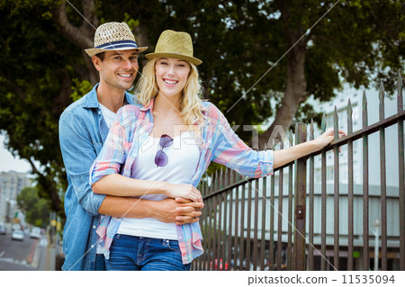 Hip young couple smiling at camera by railings 11535094