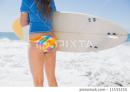 Fit surfer girl on the beach with her surfboard 11535258