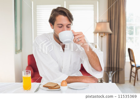 Handsome man having breakfast in his bathrobe drinking coffee 11535369