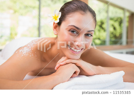 Beautiful smiling brunette lying on massage table with salt scru Beautiful smiling brunette lying on massage table with salt scru 11535385
