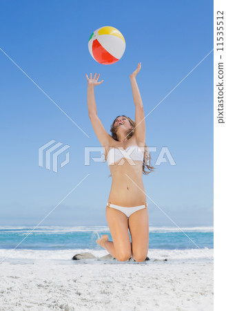 Fit blonde in white bikini throwing beach ball Fit blonde in white bikini throwing beach ball 11535512
