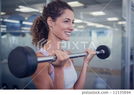 Fit smiling woman lifting barbell 11535694