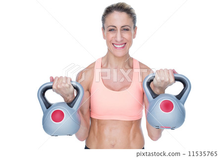 Smiling female crossfitter lifting kettlebells 11535765
