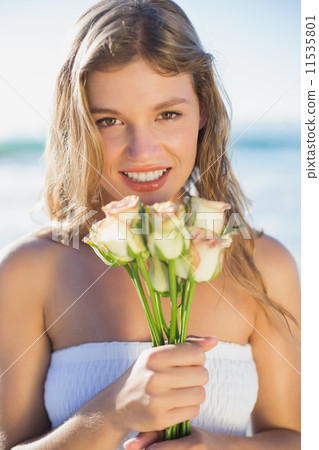 Beautiful blonde in sundress holding roses on the beach Beautiful blonde in sundress holding roses on the beach 11535801