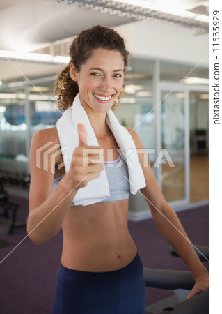 Fit woman wearing towel around shoulders showing thumbs up Fit woman wearing towel around shoulders showing thumbs up 11535929