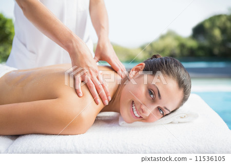 Happy brunette getting a massage poolside 11536105