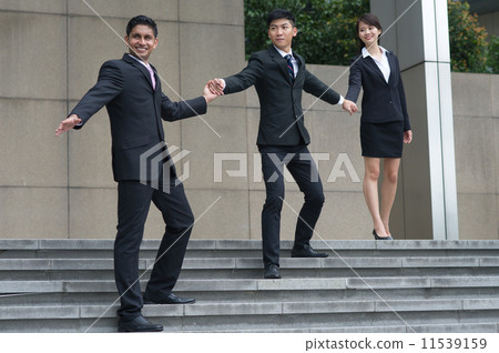 A leader leads his mult-ethnic and talented teammates by hand to walk down the stair cautiously A leader leads his mult-ethnic and talented teammates by hand to walk down the stair cautiously 11539159