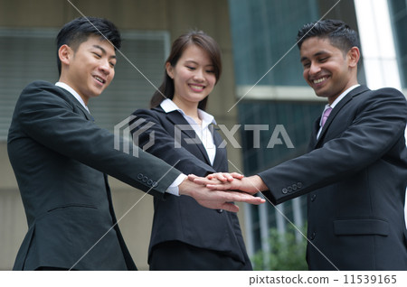 Three young, multi-ethnic and successful co-worker extended hand to show united front & team spirit Three young, multi-ethnic and successful co-worker extended hand to show united front & team spirit 11539165