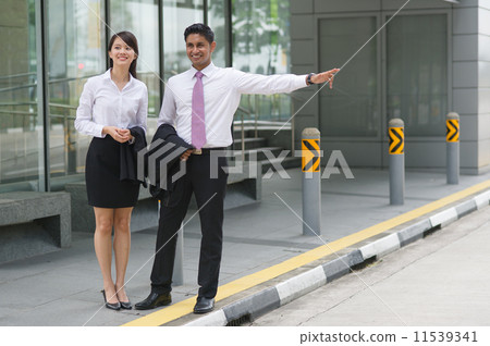 A young Indian co-worker and his Chinese female colleague waiting for Singapore Public Transport A young Indian co-worker and his Chinese female colleague waiting for Singapore Public Transport 11539341