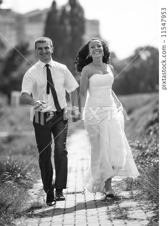 Photo of bride and groom running fast and smiling at park 11547953
