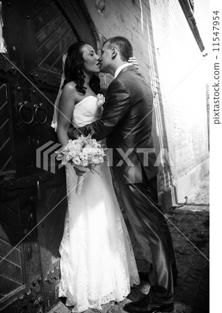 Portrait of groom kissing bride against old brick wall 11547954