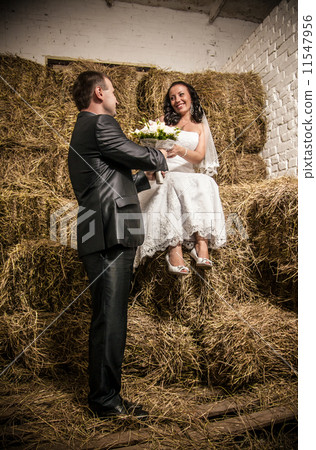 Married couple looking at each other at stable with stack of hay 11547956