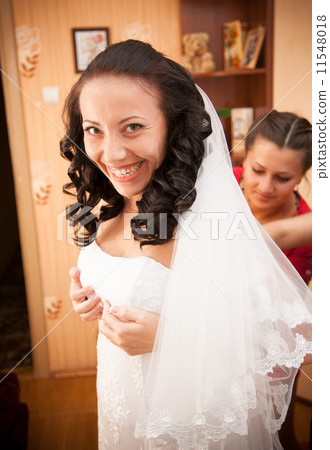 Portrait of bridesmaid tying corset on brides dress Portrait of bridesmaid tying corset on brides dress 11548018