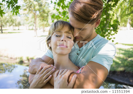 Affectionate young couple standing together in the park 11551394