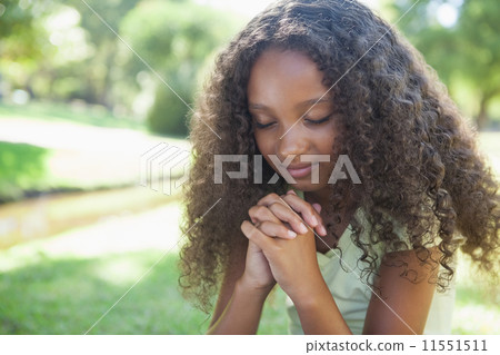 Young girl praying in the park 11551511