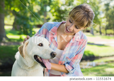 Pretty smiling blonde posing with her labrador in the park 11551674