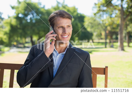 Casual businessman talking on phone on park bench 11551716
