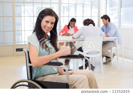 Attractive businesswoman in wheelchair gives thumbs up to camera Attractive businesswoman in wheelchair gives thumbs up to camera 11552035