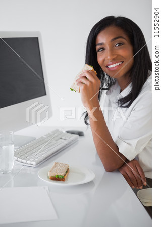 Pretty businesswoman having a sandwich at her desk 11552904