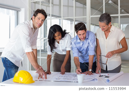 Team of architects going over blueprints with one smiling at cam 11553994