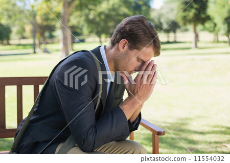 Worried businessman sitting on park bench 11554032