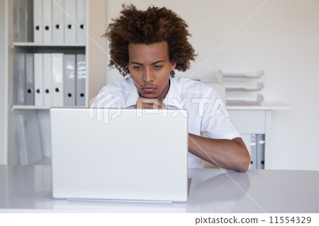Focused casual businessman using laptop at desk Focused casual businessman using laptop at desk 11554329