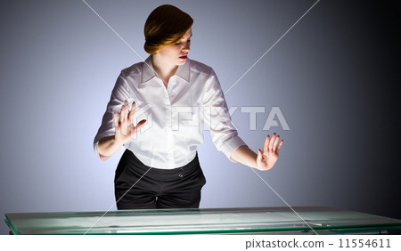 Redhead businesswoman standing and gesturing by a desk Redhead businesswoman standing and gesturing by a desk 11554611